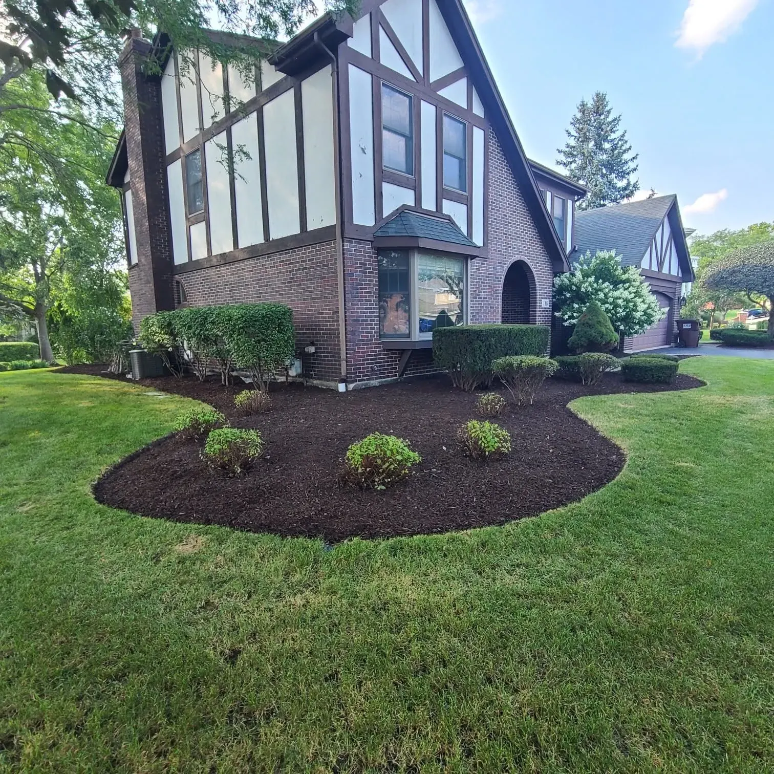 Tudor-style home with crisp curved mulch beds installed by Tello & Son's